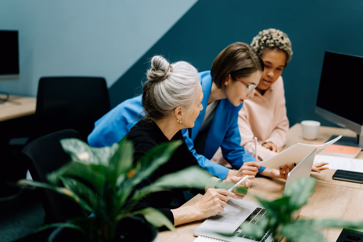 Three women sitting looking at papers in an office